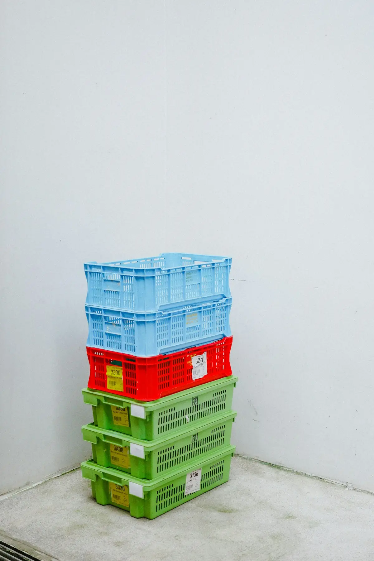 Stacked plastic crates in blue, red and green against a white wall
